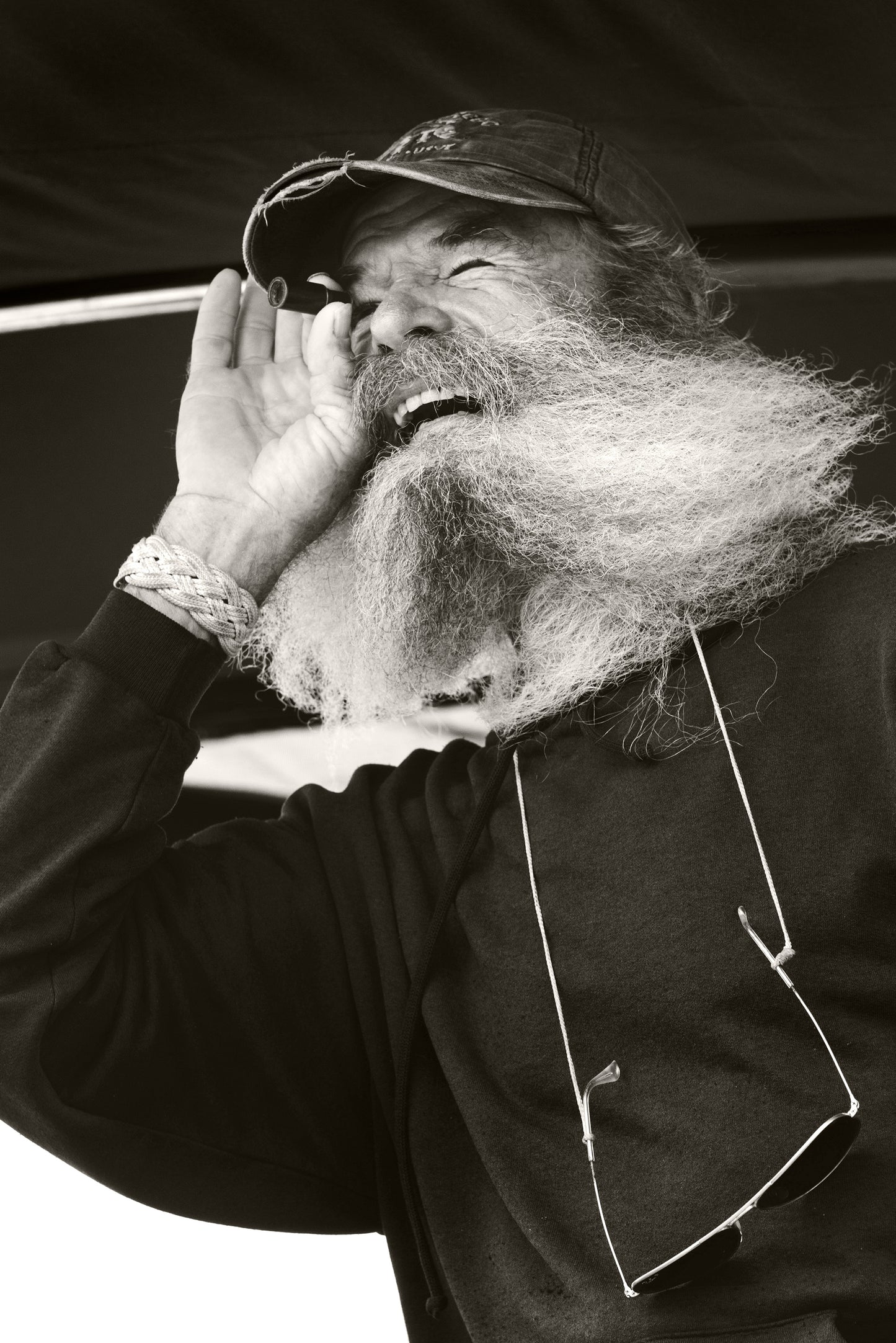 Black and white nautical portrait of a sea captain using a handheld telescope aboard a sailboat by Brian Sager